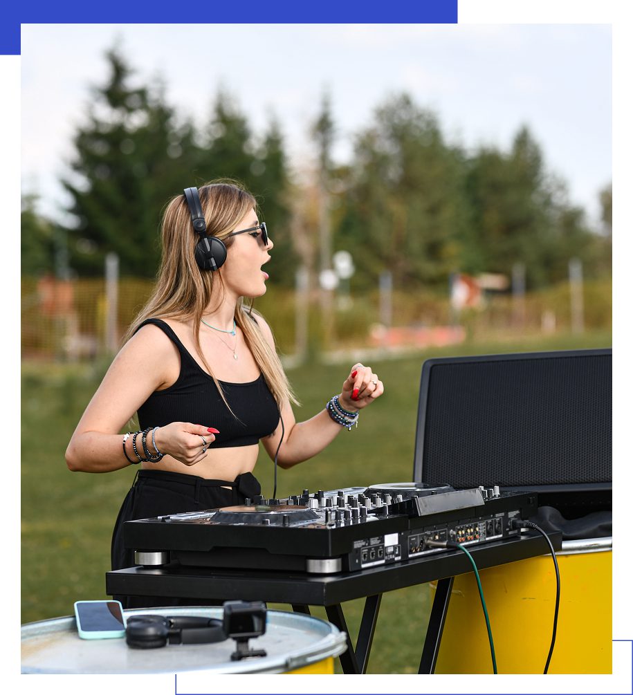 DJ performing outdoors with headphones and equipment.